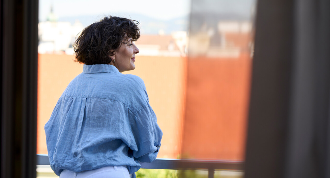 Frau genießt den Ausblick vom Balkon des Hotel Henriette in Wien.